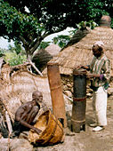 Чоловік та син поруч з високими барабанами, вирізаними із стовбурів дерев