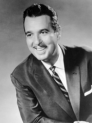 A smiling man with a thin mustache, wearing a suit and necktie