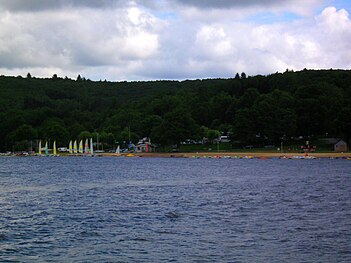 Leisure beach on the south side of the lake, with typical Plateau de Millevaches landscape in the background.