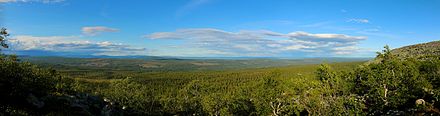 Panorama z náhorní plošiny ukazující rozlehlý les na svazích