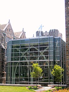 A glass building with a metal blue devil on top and arched details in the interior