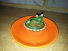 A uranium glass bowl in the shape of a cat, on top of a fiestaware plate, both previous uses of Sodium diuranate. AW U glass bowl on fiestaware plate.jpg