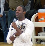 Brian McKnight, mengenakan kaus putih dan bernyanyi ke mikrofon di stadion