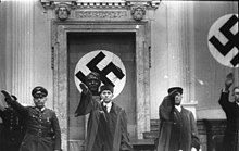 Photo of four men, two in judge's robes, with their right arms raised in the Nazi salute