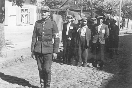 A member of the Lithuanian Security Police marching Jewish men through Vilnius, 1941