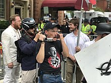 Protestors at the 2017 Unite the Right rally, which was promoted by the alt-right. One man carries the logo of Vanguard America, and another has a T-shirt depicting German Nazi leader Adolf Hitler. Charlottesville "Unite the Right" Rally (35780262984).jpg