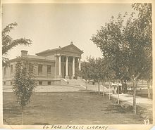 Старая фотография большого здания с ведущей к нему дорожкой, обрамленной деревьями