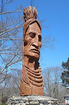 20 ft (6.1 m) high sculpture of Enishkeetompauog Narragansett in Sprague Park, Narragansett, Rhode Island. Among the tribal leaders who had attended the 1982 dedication were Princess Red Wing and Roaring Bull, who was the last traditional war chief of the Narragansett Tribe. EnishkeetompauogOblique 20160413.jpg