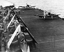 F4U-2 Corsairs of Marine Night Fighting Squadron 523 (VMF(N)-532) photographed being transported on the flight deck of Windham Bay, 12 July 1945. Two Corsairs are shown preparing to launch, perhaps to be transferred.