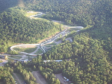 Mt. Van Hoevenberg Olympic Bobsled Run in 2005. The track (shown on the right) hosted the bobsleigh competitions for the 1932 Winter Olympics in Lake Placid. Forty-eight years later, two tracks were used with one for bobsleigh and another for luge. File BobsleighrunLP.JPG