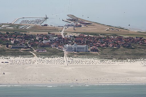 Juist (Luftbild): Blick südwärts, vorne der Strand an der Nordsee, in der Mitte der Ort Juist mit dem weißen Strandhotel Kurhaus, dahinter der hafen am Wattenmeer