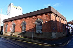 The former Hydraulic Power Station on the corner of Machell Street and Catherine Street in Bankside, Kingston upon Hull. According to both a Hull City Council heritage plaque installed in 1990 as well as the Carnegie Heritage Centre website, this opened in 1876 as the "first hydraulic system laid by Act of Parliament in England" and Hull's first "public utility", "supplying water to the Old Town and some of Hull's docks". This carried on pumping water until 1947, when it was shut down due to damage inflicted on operator Hull Hydraulic Power Company's infrastructure during the Second World War. It now seemingly functions as a car workshop.