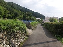 The landscape to the left is known as satoyama; a traditional human-influenced secondary forest bordering agricultural fields in Japan. The satoyama conservation movement spread in the 1980s in Japan and by 2001 there were more than 500 environmental groups involved. Kiiji, Haratani village 02.jpg