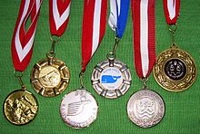 Various prize medals with obverse designs, suspension rings and ribbons typical of medals intended to be draped over the head and hung from the neck Medals.jpg