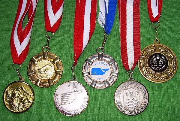 Various prize medals with obverse designs, suspension rings and ribbons typical of medals intended to be draped over the head and hung from the neck