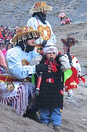 Dancers at Quyllurit'i. A ch'unchu performer can be seen behind and to the right of the child. Qoyllur Rit'i young dancer.jpg
