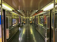 The interior of a R62A subway car used on the 42nd Street Shuttle, which was retrofitted to increase capacity. Almost all of the seats have been removed, original lighting still present.