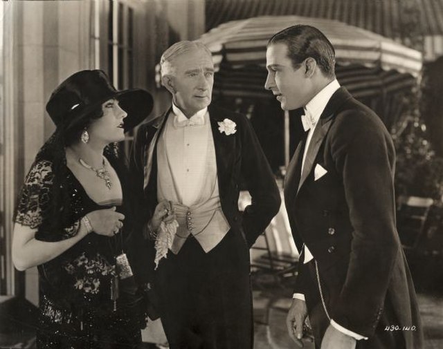 Theodora Fitzgerald and her father Captain Fitzgerald (played by Gloria Swanson and Alec B. Francis) talk to Lord Hector Bracondale (Rudolf Valentino)