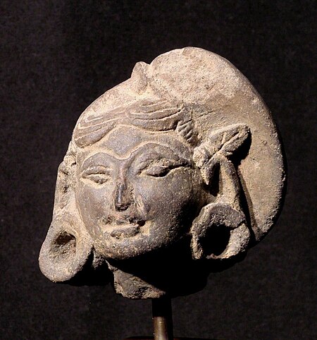 Majapahit head; 13th-15th century; terracotta; 6 x 6 x 4.2 cm. Although simply modeled, this head is very expressive and, although it is small (6 cm) the details can clearly be seen. She wears a head band and her hair, piled on the left is also tied bt the scarf. There is a leaf over her right ear. Her ear rings are large and tubular TC 245 Majapahit Terracotta head, front view..JPG