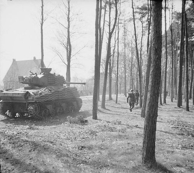 A Sherman Firefly of the 5th Canadian (Armoured) Division assists British troops of the 11th Battalion, Royal Scots Fusiliers, British 49th Infantry D