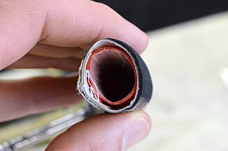 Aufgeschnittener Schlauchreifen. Innen der Schlauch (rot), umgeben von einem textilen Mantel (weiß) mit der gummierten Lauffläche