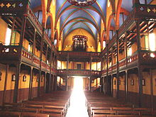 Innvendig utsikt over en kirke, med to nivåer av gallerier.