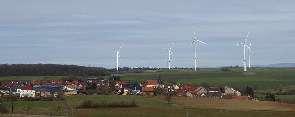 Dorf in Franken mit seinen PV-Anlagen vor Windrädern