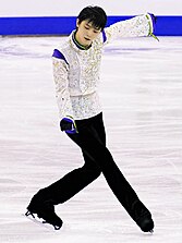 2015年グランプリファイナルのフリースケーティング『SEIMEI（せいめい）』の演技中の羽生結弦の写真。足をクロスさせ、左手は横、右手は前に差し出している。目線は右手の方向を向いている。