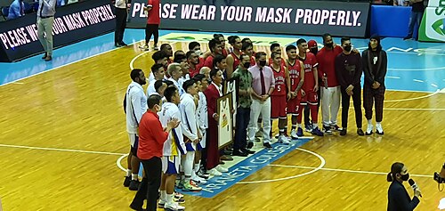 Mark Pingris and Peter June Simon poses with their framed retired jerseys together with the players of Magnolia Hotshots and Barangay Ginebra San Miguel during their jersey retirement ceremony held at halftime between the two teams on December 25, 2021. 2021-1225 PBA Mark Pingris and Peter June Simon jersey retirement.jpg