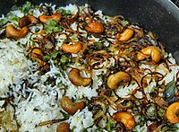 ביריאני; מנת אורז הודית קלאסית הכוללת בצל ואגוזי קשיו מטוגנים, המקושטת במעט ירק.