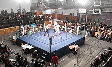 Traditional judging system, with four judges ringside, at each side of the ring, and one judge in the ring (also being a referee of the match) Combat de boxe amateur a Paris.jpg