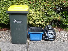 Kerbside collection bins in Dunedin, New Zealand. The yellow-liddied wheelie bin is for non-glass recyclables, and the blue bin is for glass. The two bins are collected on alternating weeks. Official council bags are used for general household waste, and are collected weekly. Dunedin City recycling bins, New Zealand, March 2011.JPG