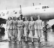 A black and white photograph of a Martin 2-0-2 aircraft with six cabin crew standing in front of the aircraft