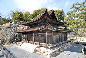 Wooden building with a hip-and-gable roof and a pent roof enclosure.