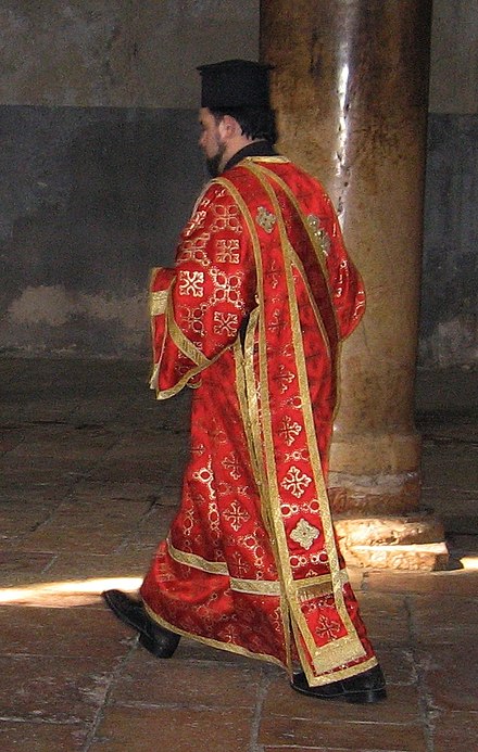 Greek Orthodox deacon in the Church of the Nativity in Bethlehem, wearing an orarion over his sticharion. On his head he wears the clerical kamilavka.