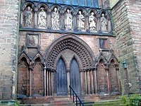 Above the ornate south doorway of Lichfield Cathedral stand seven figures carved in Roman cement. Figures from left to right, representing: Saints Augustine of Hippo, Jerome, Ambrose of Milan, Gregory the Great, John Chrysostom, Athanasius and Basil.