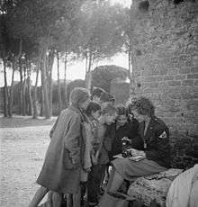 Bambini curiosi si radunano intorno al fotografo Toni Frissell, guardando la sua macchina fotografica (1945 circa)