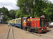 red diesel locomotive with passenger coaches