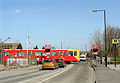 The view north along Brunton Lane, with road traffic stopped at the lights for the level crossing. Metrocar No. 4032 forms the rear of a westbound train which has just left Platform 2, to the right Spring 2001