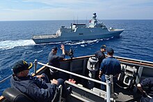 U.S. Navy Cmdr. Russell Caldwell waves to the Turkish corvette TCG Heybeliada (F 511) from aboard the guided missile destroyer USS Ross (DDG 71) in the Mediterranean Sea during a passing exercise Sept 140902-N-IY142-159.jpg
