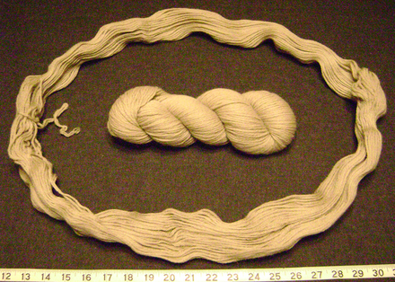 A hank of wool yarn (center) is uncoiled into its basic loop. A tie is visible at the left; after untying, the hank may be wound into a ball or balls suitable for crocheting. Crocheting from a normal hank directly is likely to tangle the yarn, producing snarls.