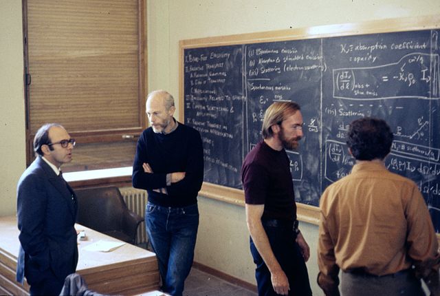 Discussion in the main lecture hall at the École de Physique des Houches (Les Houches Physics School), 1972. From left, Yuval Ne'eman, Bryce DeWitt, K