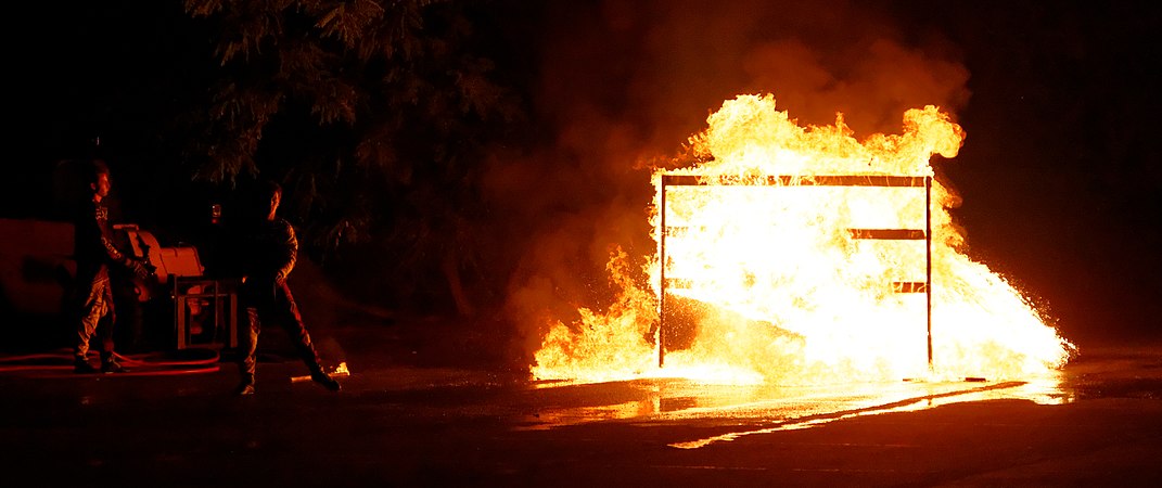 Passage dans le feu, d'une voiture à laquelle s'accroche un cascadeur (sur le toit).