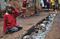 Chlapec sedí u otevřené kanalizace na ulici, 2012
