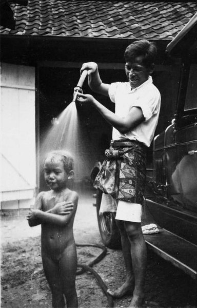 File:COLLECTIE TROPENMUSEUM Kind krijgt een douche met de tuinslang tijdens het wassen van de auto van de familie C.H. Japing in Palembang TMnr 60051099.jpg