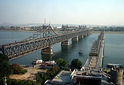 Vlevo most Čínsko-korejského přátelství, vpravo starší zničený most končící uprostřed řeky