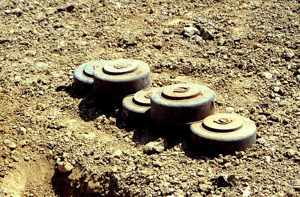 A stack of five M15 mines dating from the 1960s. The top two mines show additional fuze wells