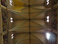 Detailed view of the ceiling of the nave of Saint Patrick Church. Viewed perpendicularly to the ground; straight up toward the ceiling. The ceiling is supported by ribbed vaults. Clerestory windows are visible along the both sides of the length of the nave, with murals immediately below. Located at 284 Suffolk Street, Lowell, Massachusetts.