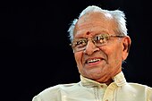 Photograph of a smiling old man wearing glasses.