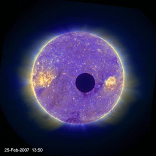 The bright disk of the Sun, showing many coronal filaments, flares and grainy patches in the wavelength of this image, is partly obscured by a small dark disk: here, the Moon covers less than a fifteenth of the Sun.